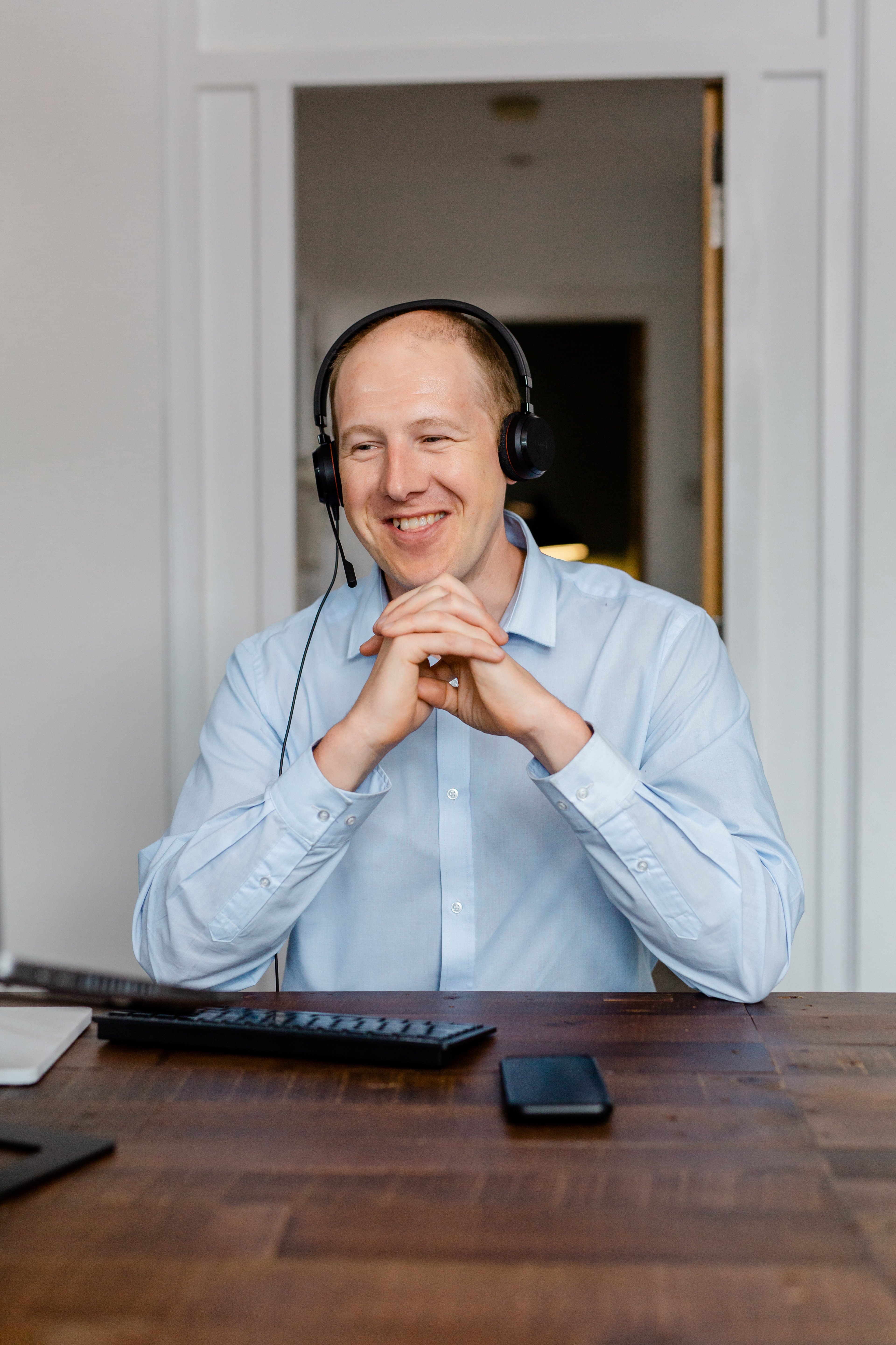 Datel's John Hesketh wearing a blue shirt and wireless headset, speaking to a customer from his home office