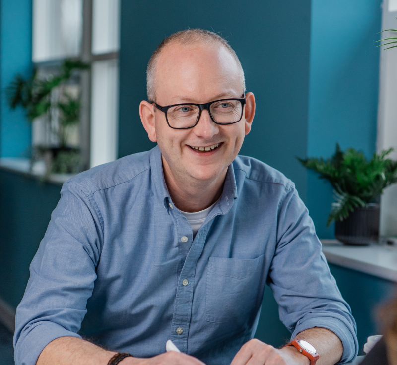A man wearing glasses and a blue shirt smiling