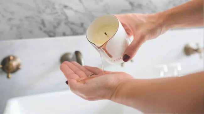 Close up of a person's hands as they empty the melted wax from a NEOM candle