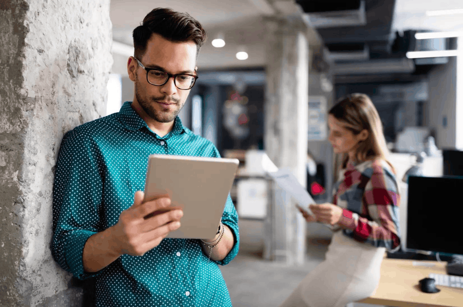 A man with glasses holding a tablet