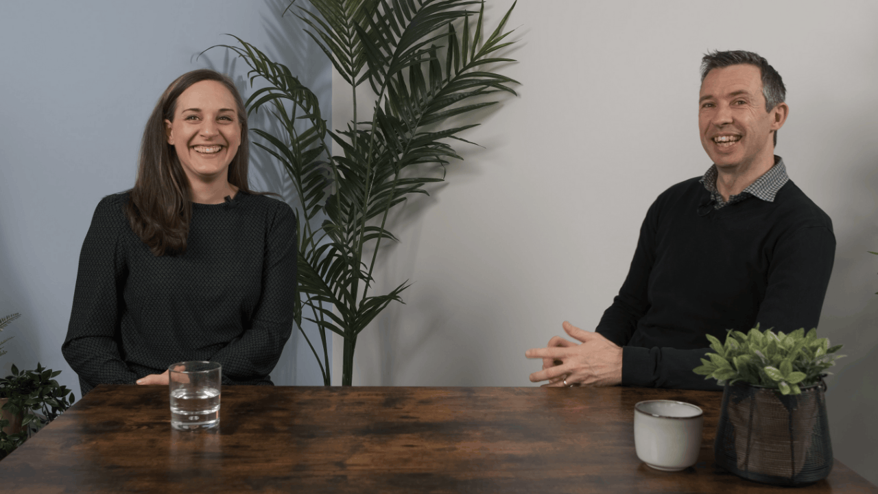 A man and woman sat at a table smiling