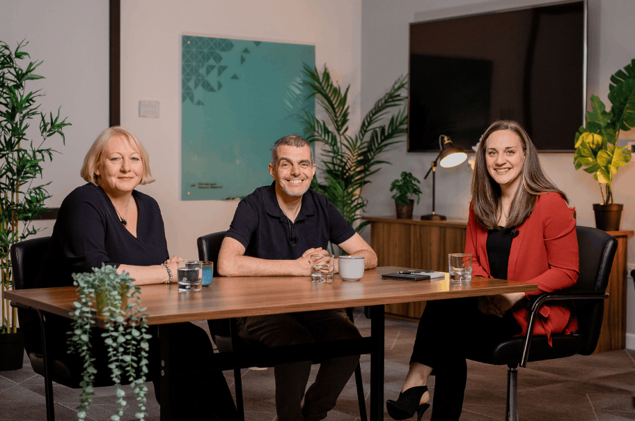 A man and two women smiling sat at a table