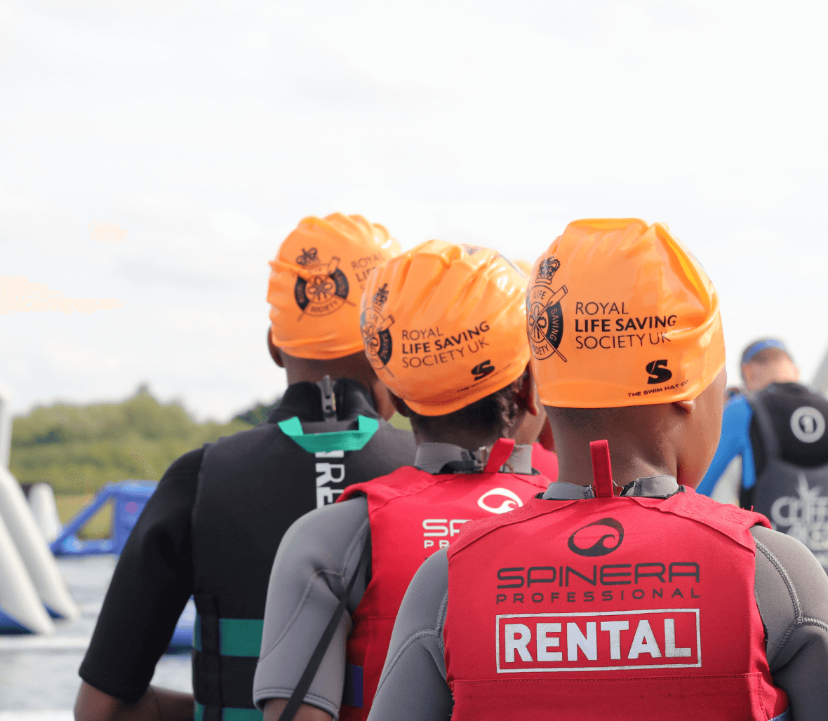 Three people wearing life jackets and swimming caps