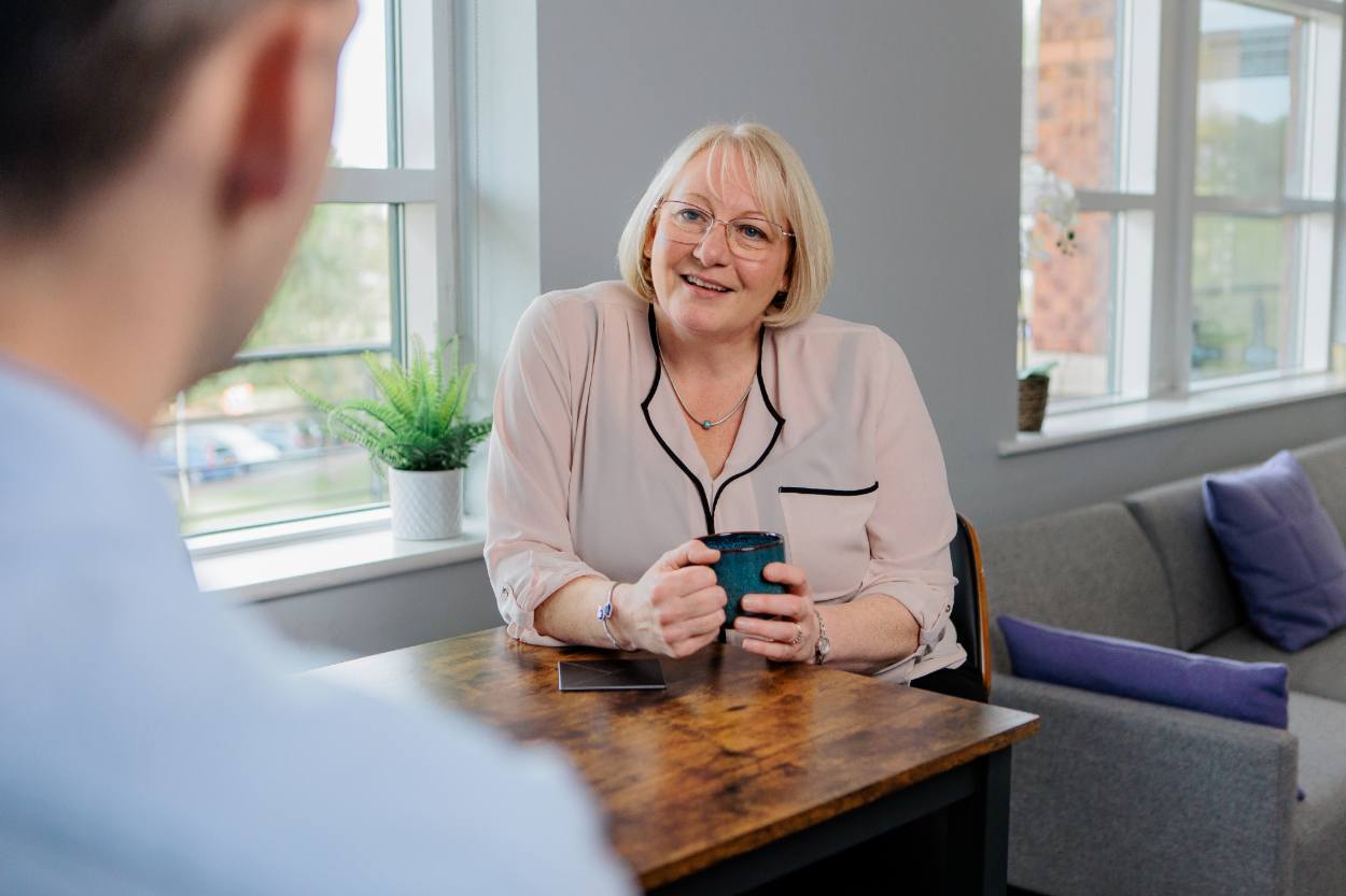 A woman holding a mug whilst smiling
