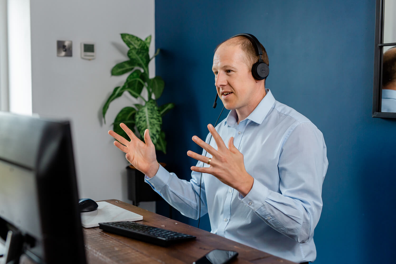Datel employee wearing a blue shirt and a wireless headset, supporting a customer from his home office